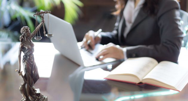 A professional woman in a suit seated at a desk, focused on her laptop, exemplifying a modern work environment.