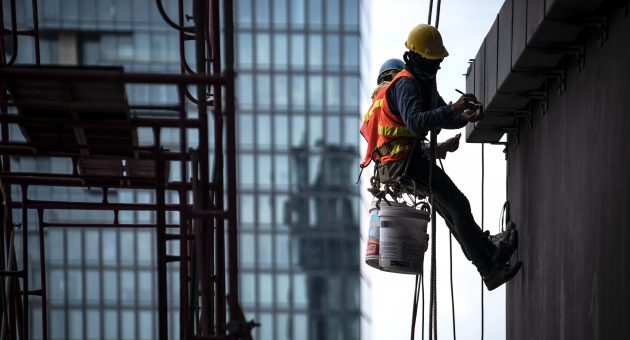 Construction worker wearing safety harness and safety line working at high place
