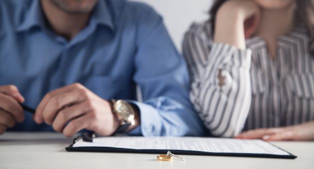 Couple with divorce contract and ring on desk. Divorce