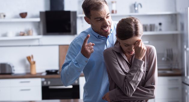 aggressive man in shirt screaming at crying wife during quarrel
