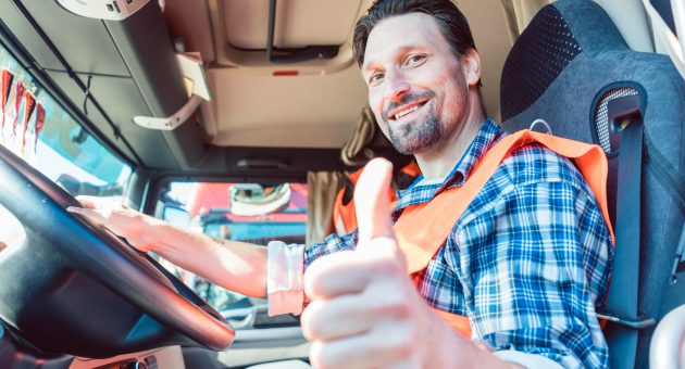 Truck driver man sitting in cabin giving thumbs-up