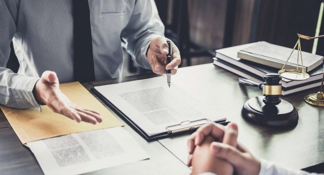 A lawyer and a client engaged in discussion at a desk, reviewing legal documents together in a professional setting.