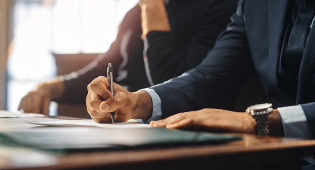 Court of Justice and Law Trial: Male Barrister Writes Down Arguments for Defence Strategy. African American Attorney Lawyer Fight for Freedom of His Client with Supporting Evidence. Close Up.