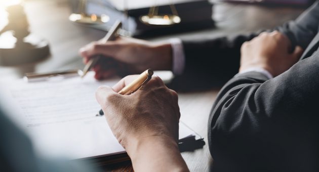 Judge gavel with Justice lawyers having team meeting at law firm in background. Notary with client in office