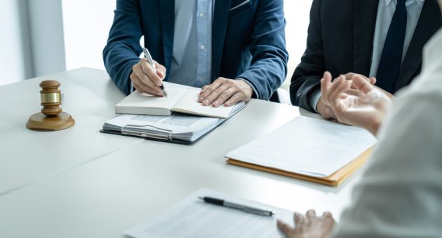 A gathering of people around a table, with a judge overseeing the conversation and deliberations among them.